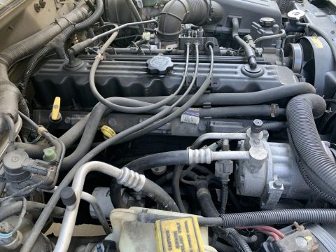 2000 Jeep Cherokee - The engine compartment of a Jeep shows various components and fluid reservoirs.