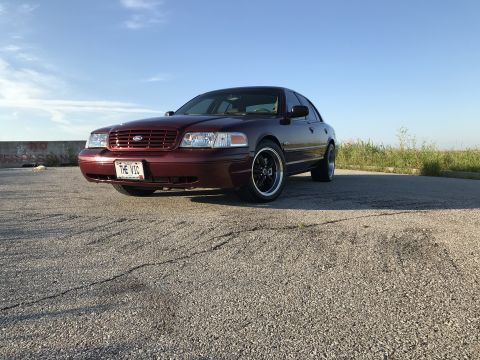2004 Ford Crown Victoria - This 2004 Ford Crown Victoria features a deep red paint job, aftermarket wheels, and a personalized license plate.