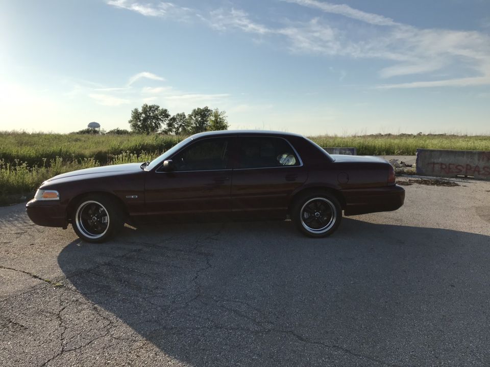 Maroon Ford Crown Victoria with black rims parked on asphalt