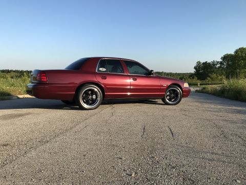 2004 Ford Crown Victoria - Side view of a red 2004 Ford Crown Victoria with black aftermarket wheels.