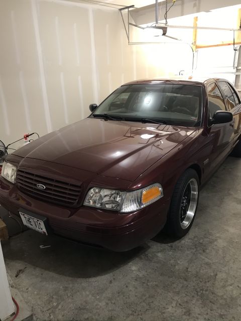 2004 Ford Crown Victoria - Maroon Ford Crown Victoria with aftermarket wheels parked in a garage.