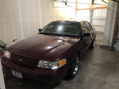 2004 Ford Crown Victoria - This maroon 2004 Ford Crown Victoria is shown in a garage, custom wheels and a license plate reading 'THE VIC'.