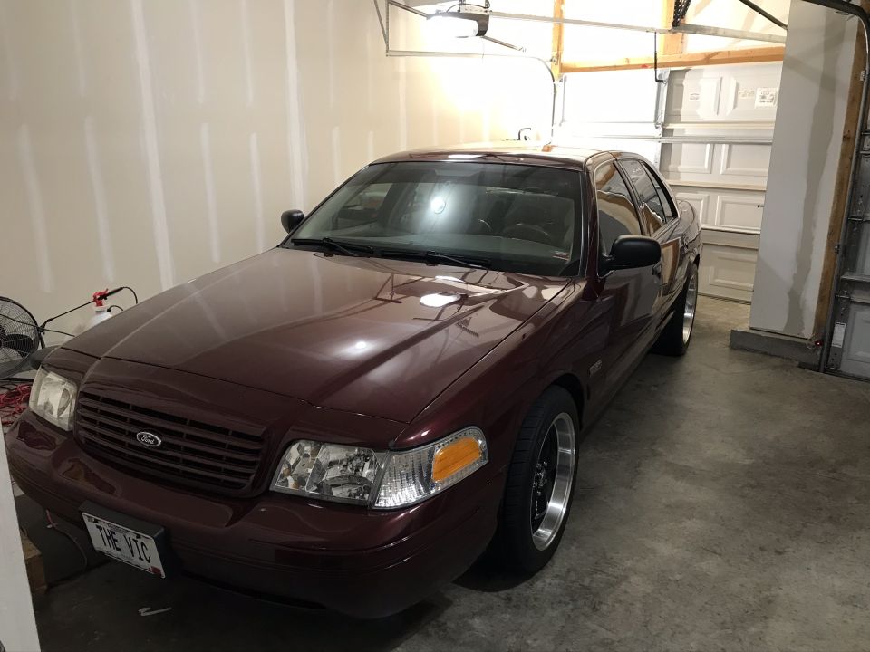 Maroon 2004 Ford Crown Victoria with custom wheels parked in a garage