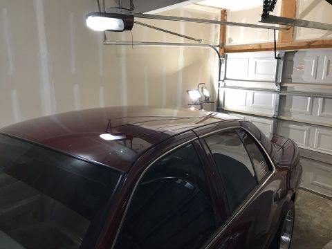 2004 Ford Crown Victoria - Maroon sedan in a garage with the door open, showing the side profile. Supermotors.net logo is visible.