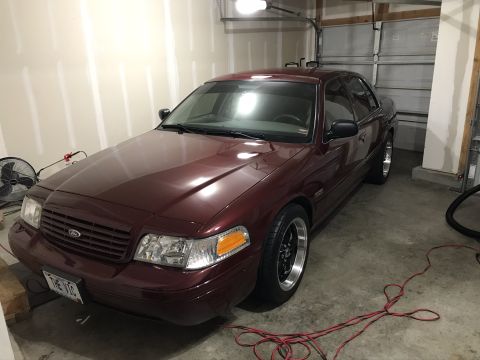 2004 Ford Crown Victoria - Maroon Ford Crown Victoria with aftermarket wheels parked in a garage.
