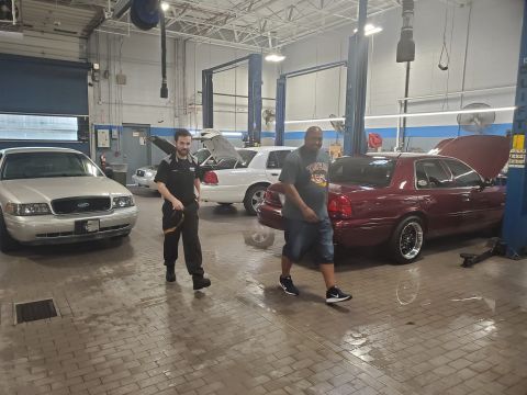 2004 Ford Crown Victoria - A silver 2004 Ford Crown Victoria is parked in a service bay with other vehicles.