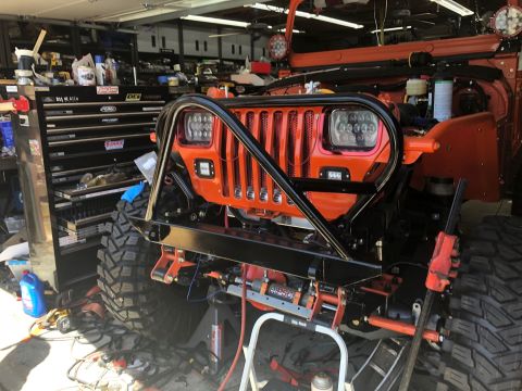 1992 Jeep Wrangler - A custom-built orange Jeep Wrangler sits in a garage, equipped with a heavy-duty bumper and winch system.