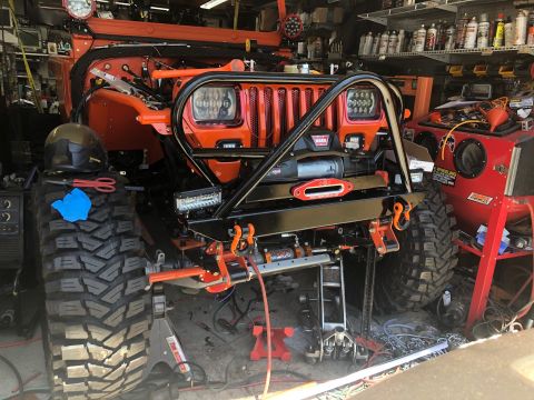 1992 Jeep Wrangler - This heavily modified 1992 Jeep Wrangler features extensive aftermarket armor, including a winch and custom bumper, in a garage setting.