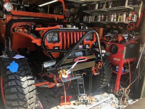1992 Jeep Wrangler - A modified Jeep Wrangler is parked in a garage, undergoing some work with tools and equipment around it.