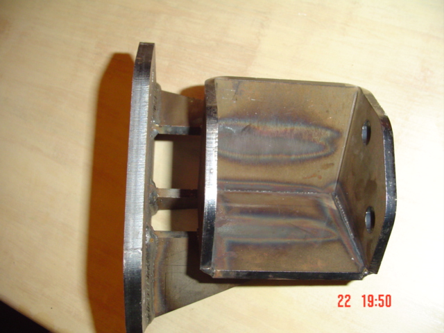 Welded steel bracket with mounting holes, placed on a wooden surface