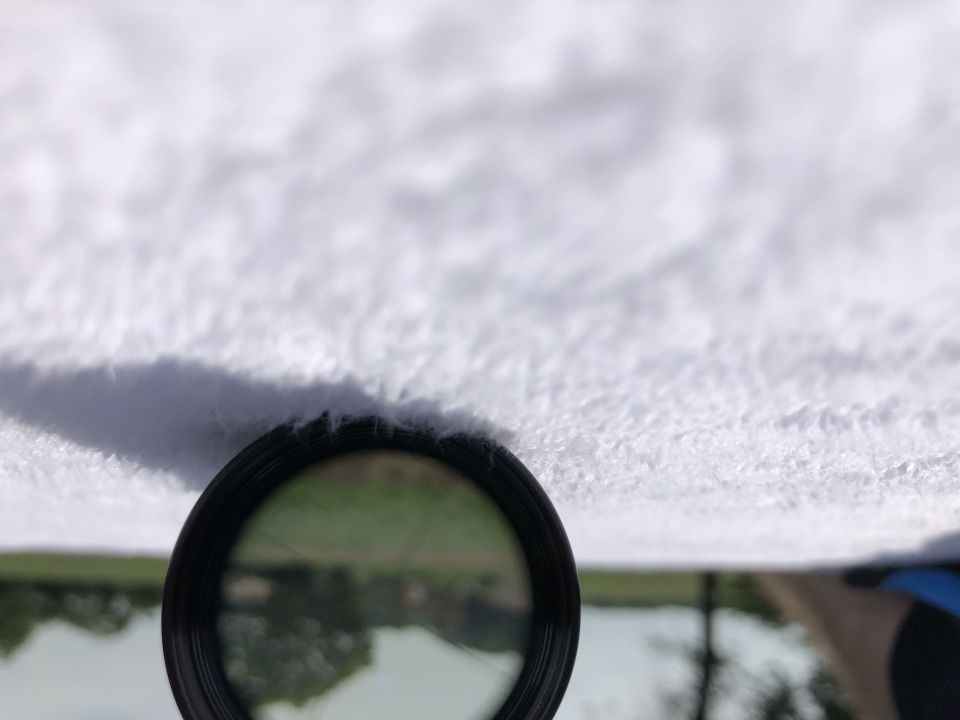 Close-up of a car's headliner with a magnifying glass showing a reflection of trees and water
