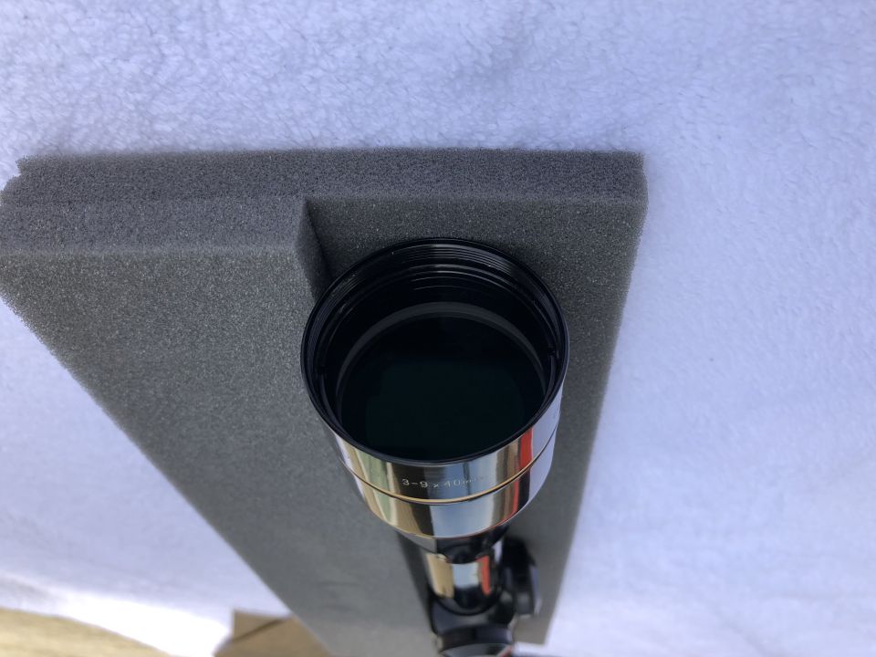 Rifle scope with 3-9x40 markings, sitting in gray foam padding