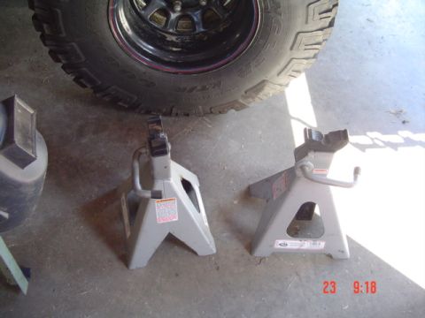 1989 Ford Bronco - Two jack stands are positioned under a large tire, suggesting vehicle maintenance is underway.