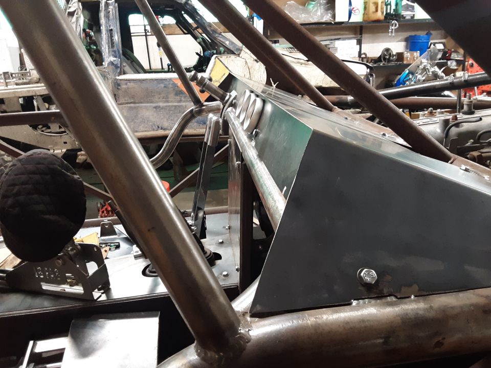 Roll cage tubing and metal panels inside a vehicle under construction. A black padded object is visible on the left