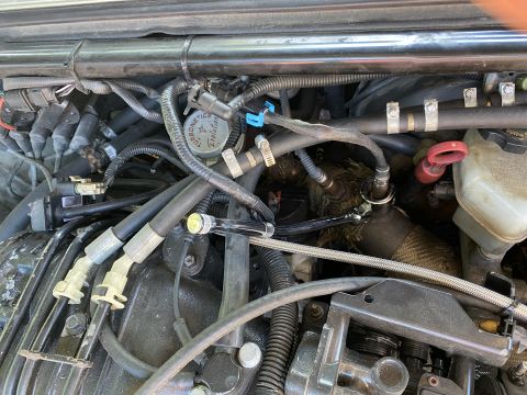 Close-up of engine bay with wrench on exhaust manifold sensor.
