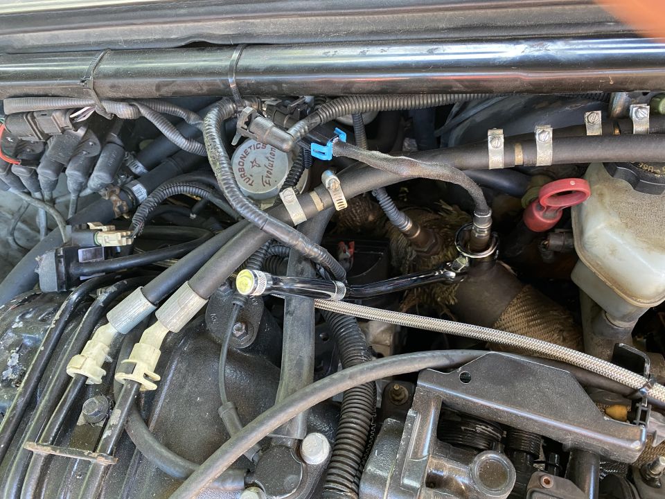 Close-up of engine bay with wrench on exhaust manifold sensor.