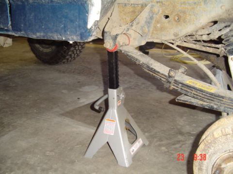 1989 Ford Bronco - Vehicle frame and suspension components are supported by jack stands in a garage.