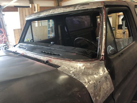 1978 Ford Bronco - Close-up view of the front cab area of a vintage Ford truck undergoing restoration. The windshield and surrounding metalwork, including the…