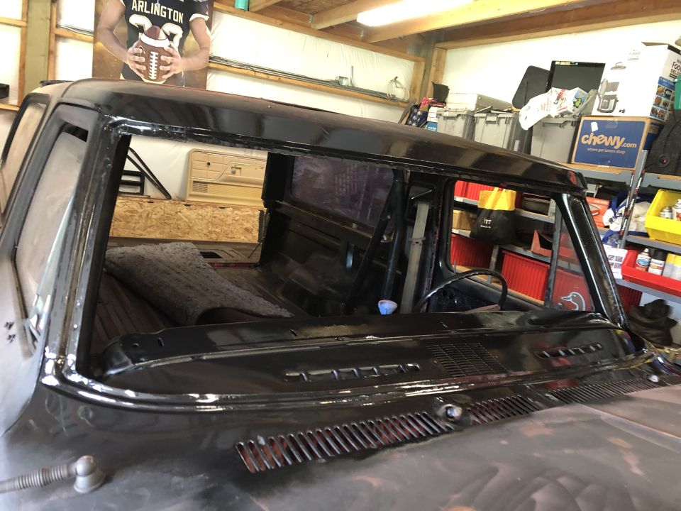 Black classic pickup truck interior, windshield area and dashboard, in a garage.