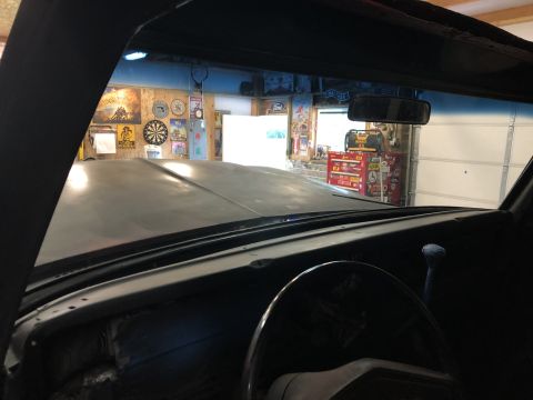 1978 Ford Bronco - View from inside a vehicle looking out through the windshield at a garage interior. The vehicle's hood and dashboard are visible in the for…