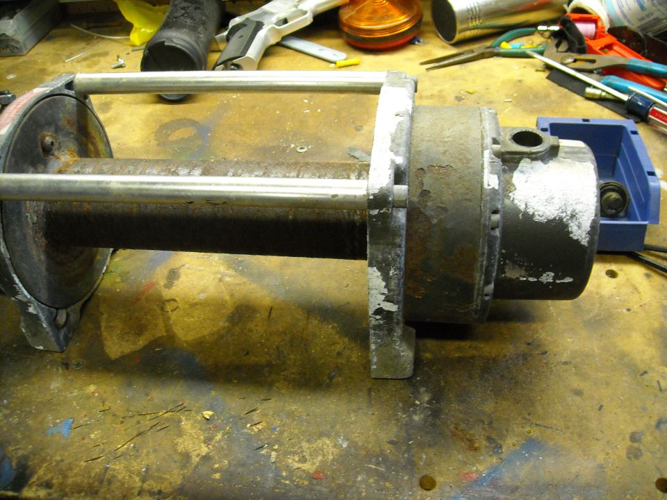 Rusty motor and metal rod assembly on a workbench with tools.