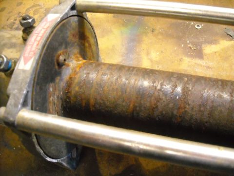 1992 Jeep Wrangler - A close-up view of a rusty winch drum with a metal frame and two silver bars. A red and white warning sticker is visible on the side of the…