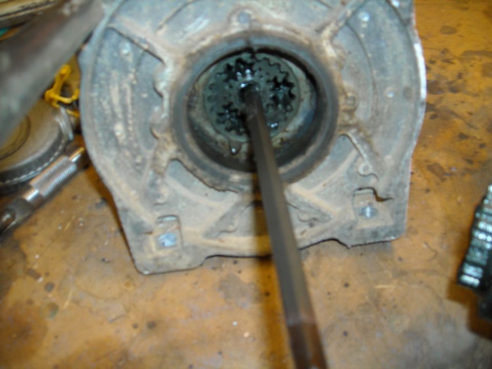 Close-up of a tool in a splined gear assembly inside a rusty housing.