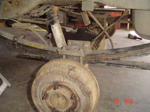 1989 Ford Bronco - This image shows the rear suspension components of a vehicle, including leaf springs and a shock absorber, with a brake drum visible.