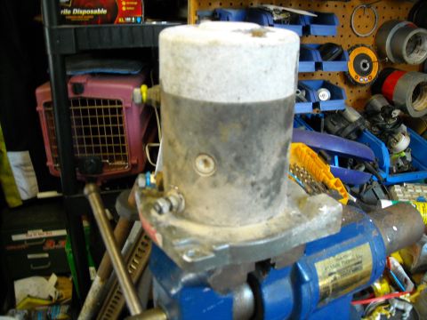 1992 Jeep Wrangler - A close-up shot of a large, cylindrical metal part, possibly a motor or pump, clamped in a blue vise. The part has a textured white top and…