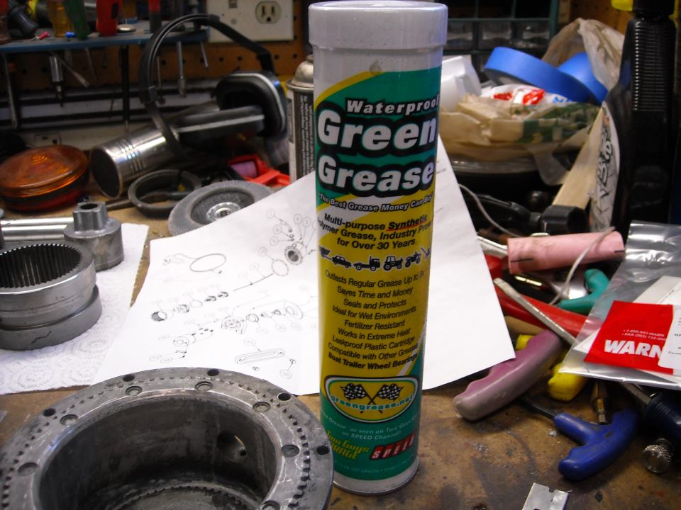 Tube of Green Grease and mechanical parts on a workbench.