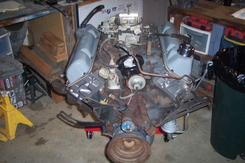 1978 Ford Bronco - A V8 engine, likely from a classic Ford Bronco, is mounted on a red engine stand. The engine features a carburetor, distributor, and grey p…
