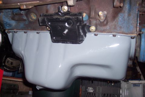 1978 Ford Bronco - A newly painted light gray oil pan is installed on a Ford V8 engine block, which is partially visible above. A black metal bracket is bolte…