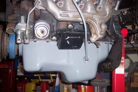 1978 Ford Bronco - A close-up view of a vehicle's engine, focusing on the oil pan and fuel pump. The oil pan is painted light gray, and a silver fuel pump is…