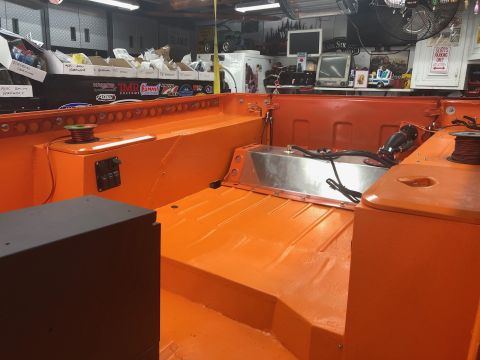 1992 Jeep Wrangler - The interior of an orange Jeep Wrangler bed is shown, featuring a custom aluminum fuel tank, electrical switches, and spools of wire. The v…