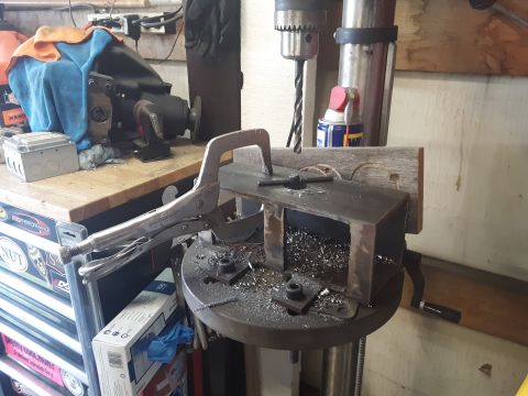 1985 Toyota Hilux - A drill press is set up in a workshop with a metal workpiece clamped to the table. Metal shavings are visible on the drill press table and…