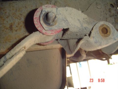 1989 Ford Bronco - Close-up view of a suspension component, possibly part of a shackle flip modification, with visible red bushings and a large bolt.