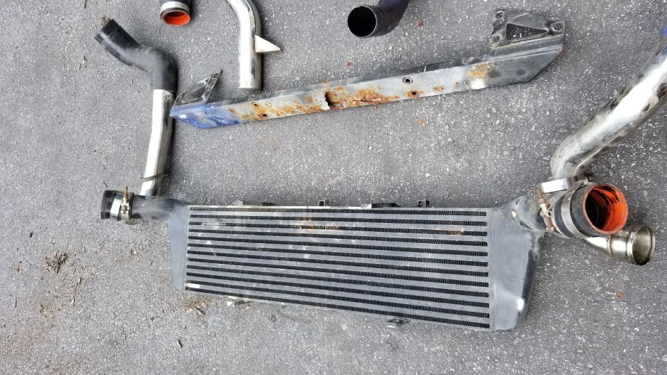 Intercooler piping and a front-mount intercooler on asphalt.