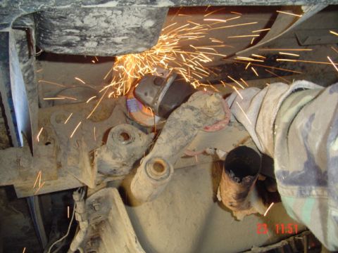1989 Ford Bronco - A person is modifying the suspension of a vehicle with an angle grinder, creating many sparks.