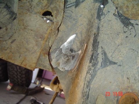 1989 Ford Bronco - Close-up of a heavily rusted vehicle frame section showing a weld repair, with a tire visible in the background.