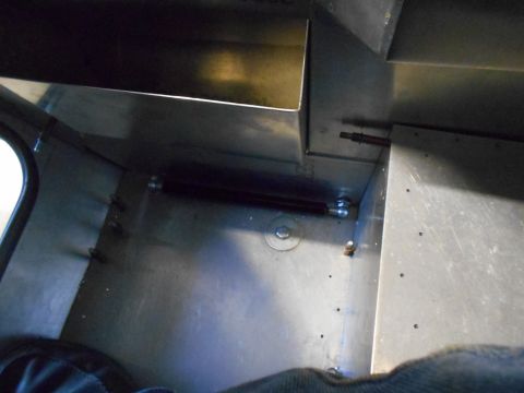 1992 Ford Bronco - The interior of a vehicle shows a metallic structure with visible rivets and fasteners. A dark cylindrical component is mounted horizontall…