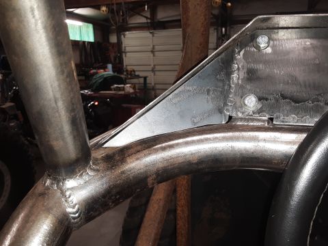 1985 Toyota Hilux - Close-up of a custom metal roll cage being welded and bolted together inside a vehicle. The scene appears to be a workshop with tools and g…
