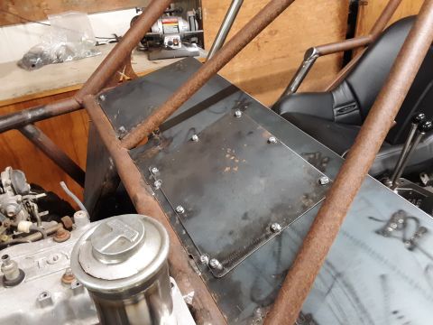 1985 Toyota Hilux - Close-up view of a custom metal fabrication project, likely for a vehicle build, showing a metal plate bolted onto a rusty metal frame. A p…