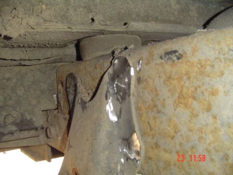 1989 Ford Bronco - Close-up of a rusted vehicle frame showing welds and a rubber bushing, likely part of a suspension modification.