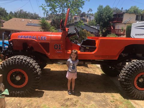 1992 Jeep Wrangler - An orange, lifted Jeep Wrangler, nicknamed "General Lee" with the number "01" and "Jeep" text on the hood, is parked outdoors with a young…