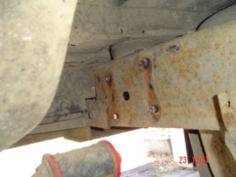 1989 Ford Bronco - Close-up of a suspension bracket with a red bushing, showing rust and modifications.