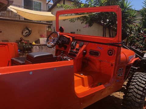 1992 Jeep Wrangler - The interior of an orange Jeep Wrangler is shown, featuring a dashboard with gauges, switches, a steering wheel, and a black seat. The vehi…