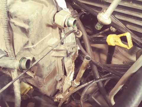 1996 Ford Bronco - A close-up view of a cluttered engine bay, showing various hoses, tubes, and a yellow dipstick with "TRANS FLUID" visible. The area appears…