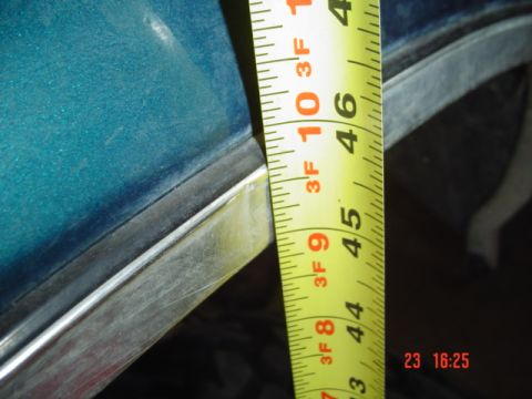 1989 Ford Bronco - Measuring the clearance on a teal vehicle body panel with a tape measure.
