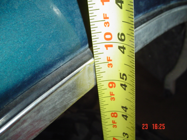 Yellow measuring tape against teal car body, showing 44-46 inches