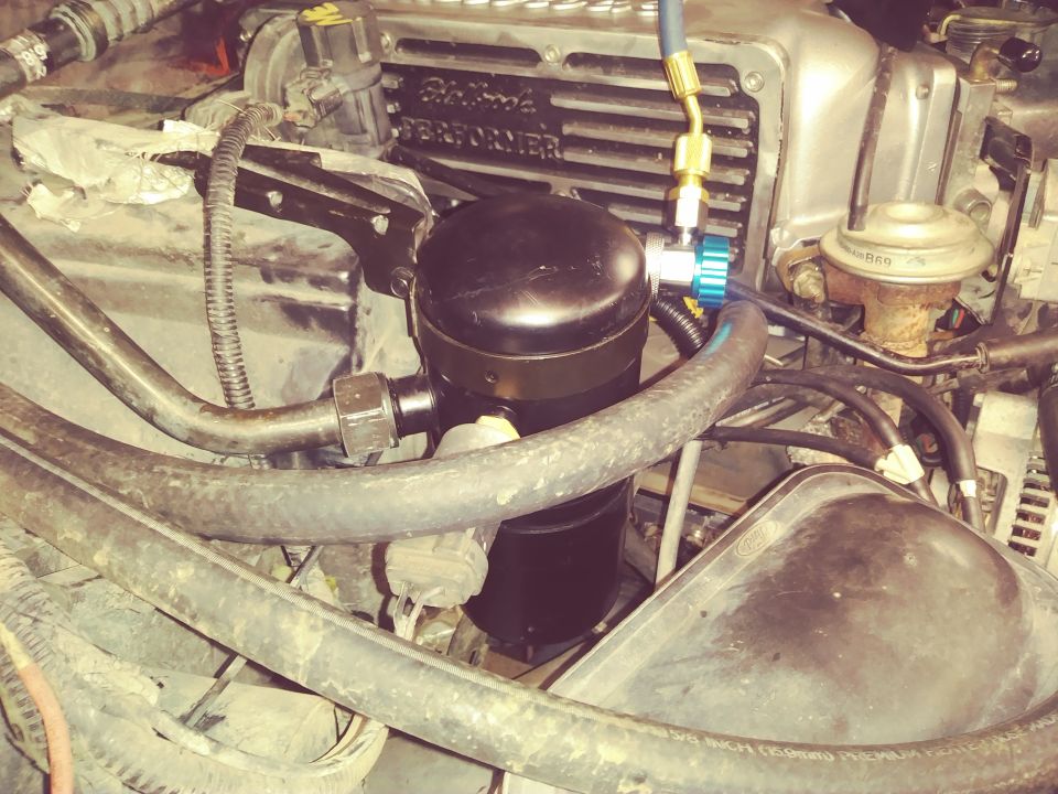 Engine bay of a 1996 Ford Bronco showing AC components and hoses.